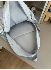 Vue rapprochée du sac à dos ouvert, avec doublure gris clair rembourrée et tissu à pois