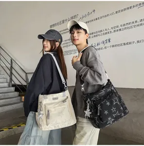 Deux personnes portent des sacs étoilés ivoire et noir, avec poche zippée et breloque assortie.