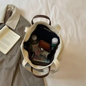 Cremefarbene Canvas-Tasche mit braunen Ledergriffen, von oben offen mit geräumigem Innenfach