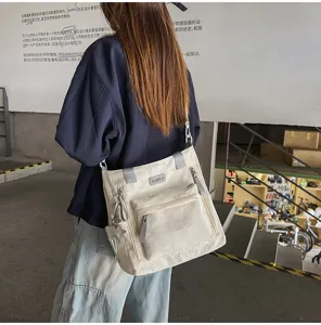 Vue arrière d’un modèle portant un sac crème à poches zippées et orné d’un pendentif étoile