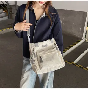 Une femme porte un sac bandoulière crème à étoiles, avec poches zippées et breloque métallique