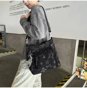 Une personne porte un sac noir à imprimé étoiles, avec poche avant et breloque argentée
