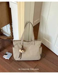 Sac beige à deux anses et pendentif ourson en peluche léopard, posé sur un sol en bois