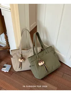 Deux cabas en nylon beige avoine et vert olive, avec breloques léopard en peluche, sur un parquet
