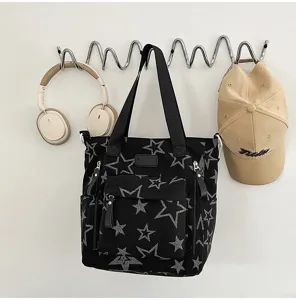 Sac noir en tissu à étoiles grises, avec poches zippées à l’avant, suspendu à un crochet mural