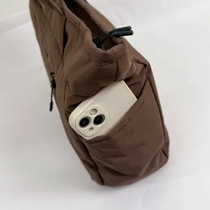 Sac cabas léger en nylon brun, avec fermeture zippée et poche latérale contenant un smartphone