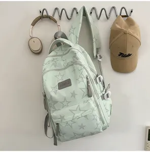 Vue du sac à dos vert menthe à étoiles grises, avec poches zippées et sangles réglables au mur