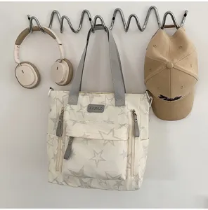 Sac crème à imprimé étoilé suspendu au mur, avec anses grises et poches zippées à l’avant