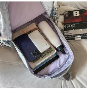 Sac à dos ouvert révélant une doublure lavande, avec des livres, des téléphones et une bouteille.