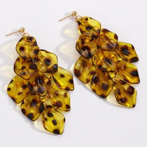 Primo piano di petali in resina ambrata traslucida con macchie effetto tartaruga e ganci dorati
