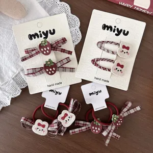 Flat lay of strawberry-patterned plaid bows and plush bunny hair clips displayed on cards