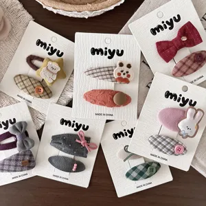 Vista cenital de pinzas de tela con animales bordados, lazos y cuadros, presentadas en tarjetas