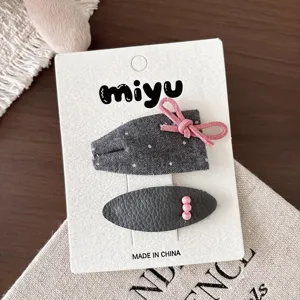 Primer plano de dos pinzas grises: lazo de tela con puntos, cordón rosa y clip de cuero sintético