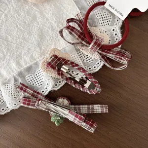 Close-up of red plaid hair bows, a scrunchie and metal clips with cream heart and green flower