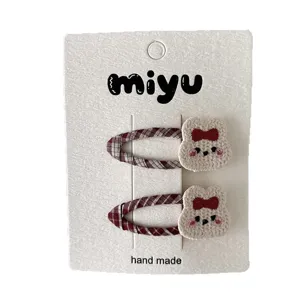 Pair of red plaid children's hair clips with knitted bear charms and bows, shown front-facing