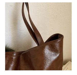Close-up of a soft brown faux-leather bag with a waxy sheen and two long shoulder straps