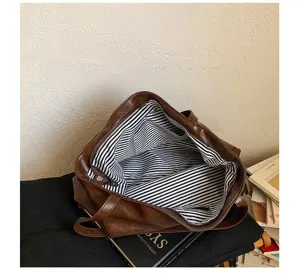 Open brown tote bag showing black-and-white striped lining, zip closure, and double handles