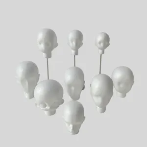 Nine white foam head forms in varied sizes, some with metal rods, on a light gray background