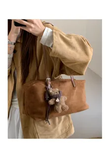 Selfi ante el espejo con un bolso marrón efecto ante, un osito de peluche colgante y asas visibles