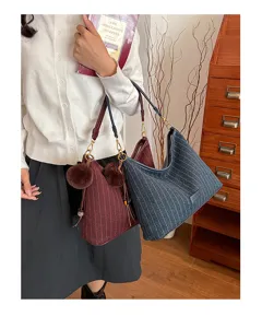 Twee fijn gestreepte tassen in bordeaux en marineblauw, met pomponhangers en goudkleurige details
