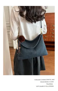 Achteraanzicht van een vrouw met een blauwe tas met fijne strepen, leren banden en bruine pompon