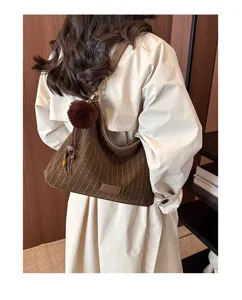 Achteraanzicht van een vrouw met bruine gestreepte tas, donkere rand en pluizige pompon als versiering