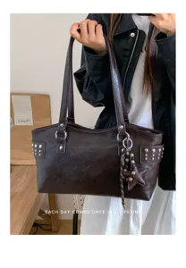 Bolso marrón oscuro con bolsillos tachonados, estrella colgante y cuentas, mostrado en la mano