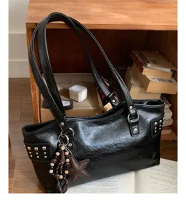 Bolso negro brillante con tachuelas y colgante de estrella, junto a una estantería de madera