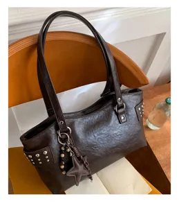 Detalle de bolso marrón oscuro de piel sintética con tachuelas, cuentas de madera y dije de estrella