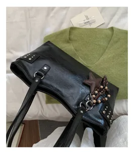 Detalle del cuero sintético negro con tachuelas, anillas y estrella decorada con cuentas y borla colgante