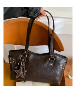 Detalle de un bolso tote de piel sintética marrón oscuro, con tachuelas, estrella y cuentas