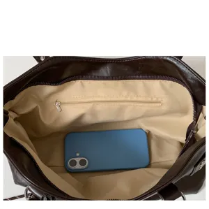 Detalle del interior del bolso abierto con forro beige, bolsillo con cremallera y herrajes plateados