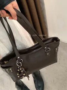 Bolso marrón oscuro de polipiel con doble asa, tachuelas plateadas, cremallera y colgante de cuentas
