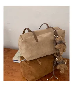 Dos bolsos beige y marrón con textura de ante, asas de efecto piel y un colgante de oso de peluche