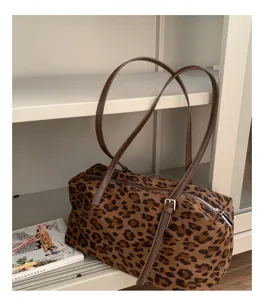 Bolso de leopardo con asas largas marrones, sobre una estantería blanca junto a una revista