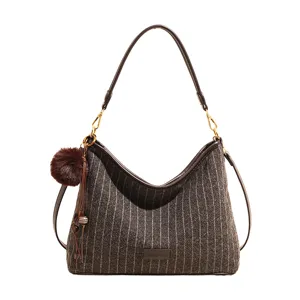 Bruine gestreepte schoudertas met wollook, leren riemen, goudkleurige details en pomponhanger