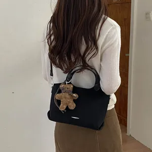 Zwarte suède shopper met afneembare schouderband en pluchen berenhanger, crossbody gedragen