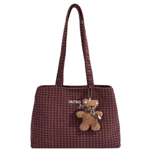 Front view showing burgundy checked fabric, white embroidery, and a teddy bear charm.