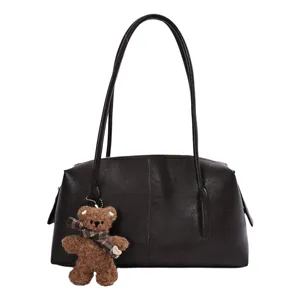 Bolso de cuero sintético marrón oscuro, visto de frente, con asas largas y un pequeño oso de peluche
