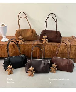 Cinco bolsos estructurados en tonos marrones y negros, presentados con pequeños adornos de oso