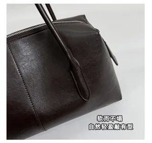 Primer plano del bolso marrón de cuero sintético, con textura, costuras, asa y cremallera