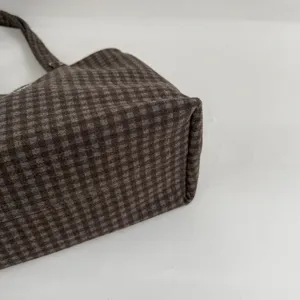 Close-up of brown checked fabric, highlighting the tote's structured side and base against white.