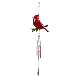 Cardenal rojo posado en una rama sobre tubos sonoros color cobre y un colgante en forma de hoja