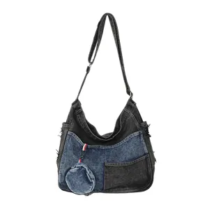 Front view of a black and blue washed denim bag with layered pockets and a round coin purse charm