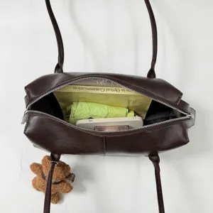 Vista superior de un bolso marrón oscuro abierto, con compartimentos con cremallera y contenido