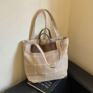 Beigefarbener Canvas-Shopper mit Karomuster, braunem Lederbesatz und zwei Henkeln, aufrecht präsentiert