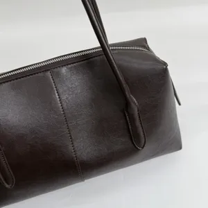 Primer plano de la superficie de polipiel marrón oscuro, con textura, costuras y cremallera
