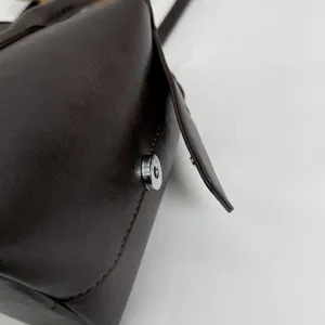 Primer plano de la superficie de cuero sintético marrón oscuro, con costuras y broche metálico