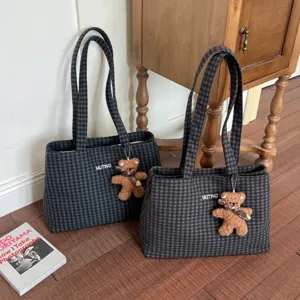 Two black and gray plaid tote bags with double handles and plush bear charms, shown side by side