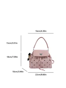 Front view of a pink dotted bag with heart-shaped metal clasp, drawstring tassel and teddy charm